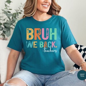 May include: A teal blue t-shirt with the text "BRUH WE BACK. -Teachers" in rainbow colors. The text has a distressed, vintage look.