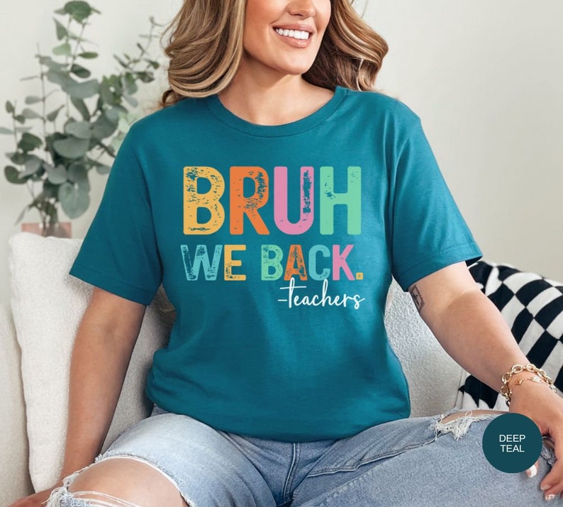 May include: A teal blue t-shirt with the text "BRUH WE BACK. -Teachers" in rainbow colors. The text has a distressed, vintage look.