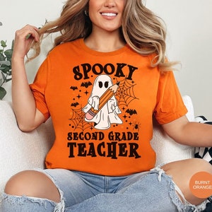 May include: A burnt orange t-shirt with a spooky ghost holding a pencil and the text "Spooky Second Grade Teacher".