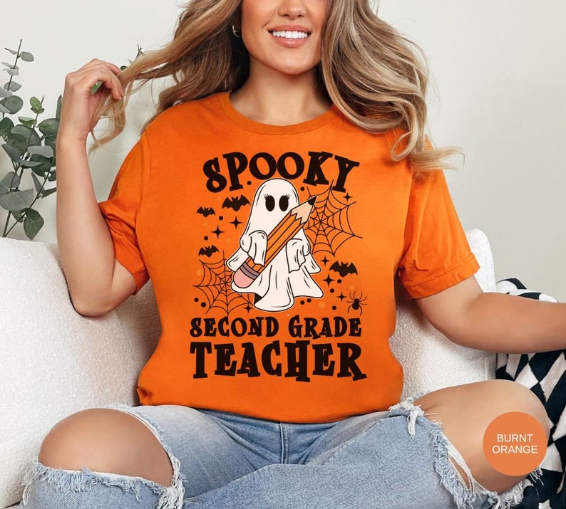 May include: A burnt orange t-shirt with a spooky ghost holding a pencil and the text "Spooky Second Grade Teacher".