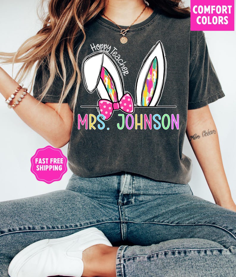 May include: A gray t-shirt with a white bunny ear design and the text "Hoppy Teacher" and "MRS. JOHNSON" in rainbow colors.