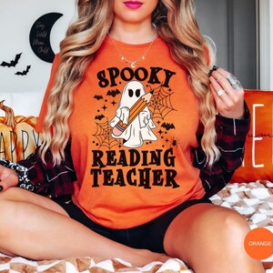 May include: Orange t-shirt with a spooky ghost holding a pencil and the text "Spooky Reading Teacher".