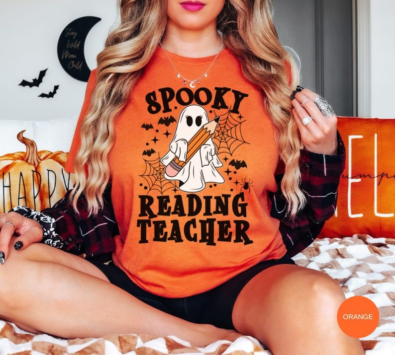 May include: Orange t-shirt with a spooky ghost holding a pencil and the text "Spooky Reading Teacher".