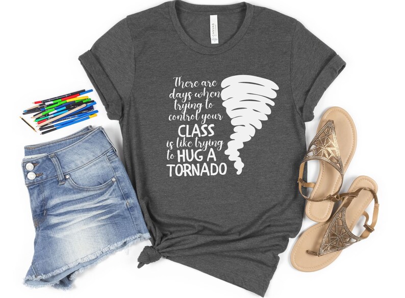 May include: A dark gray t-shirt with a white graphic of a tornado and the text "There are days when trying to control your CLASS is like trying to HUG A TORNADO".