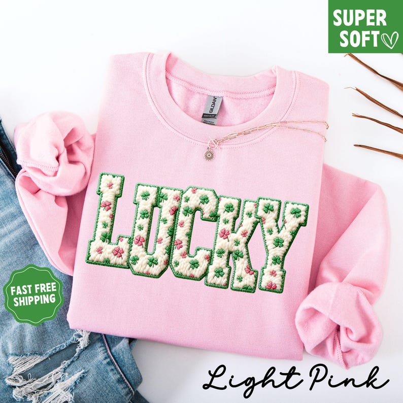 Pu&ograve; includere: Felpa rosa chiaro con la scritta "LUCKY" ricamata con trifogli verdi e fiori rosa. La felpa girocollo ha maniche lunghe. Il testo "Light Pink" si trova nella parte inferiore dell'immagine.