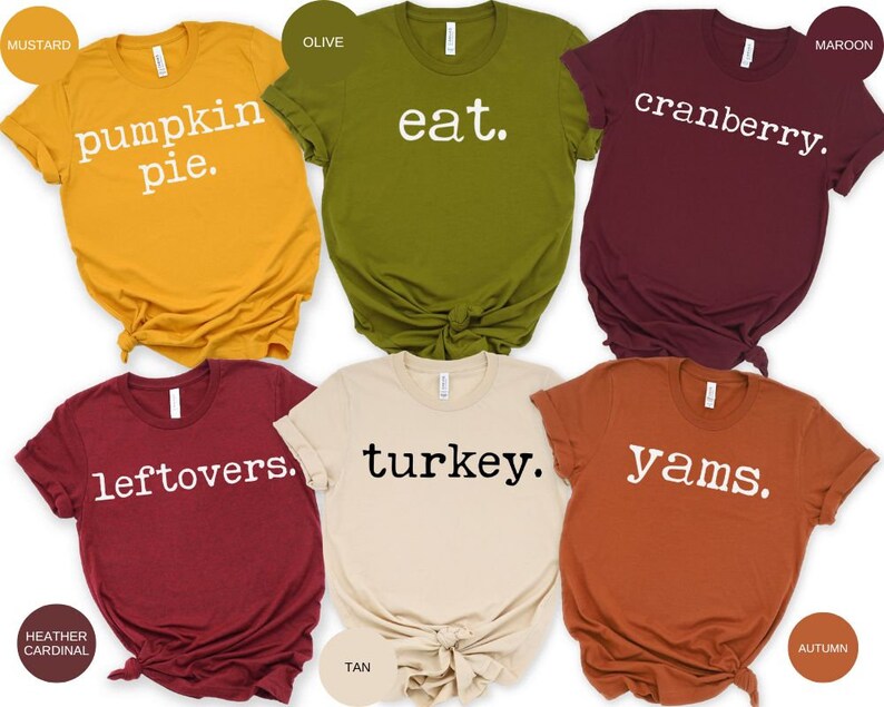 May include: Six different colored t-shirts with Thanksgiving themed text printed in white on each shirt. The shirts are mustard yellow, olive green, maroon, heather cardinal, tan, and autumn.