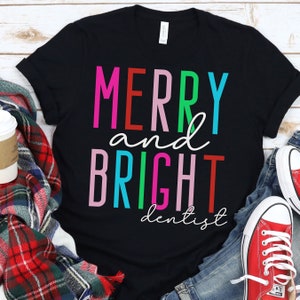 May include: Black t-shirt with the text "Merry and Bright dentist" in colorful letters. The letters are in different colors, including red, pink, green, blue, and turquoise.