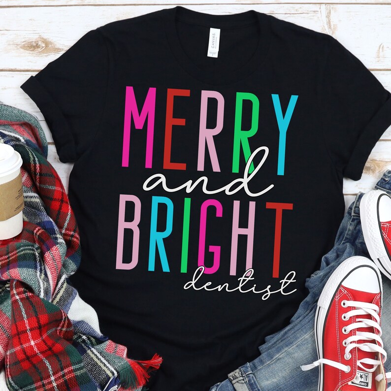 May include: Black t-shirt with the text "Merry and Bright dentist" in colorful letters. The letters are in different colors, including red, pink, green, blue, and turquoise.