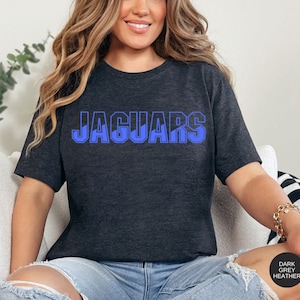 May include: A dark grey heather t-shirt with the word "JAGUARS" printed in blue on the front.