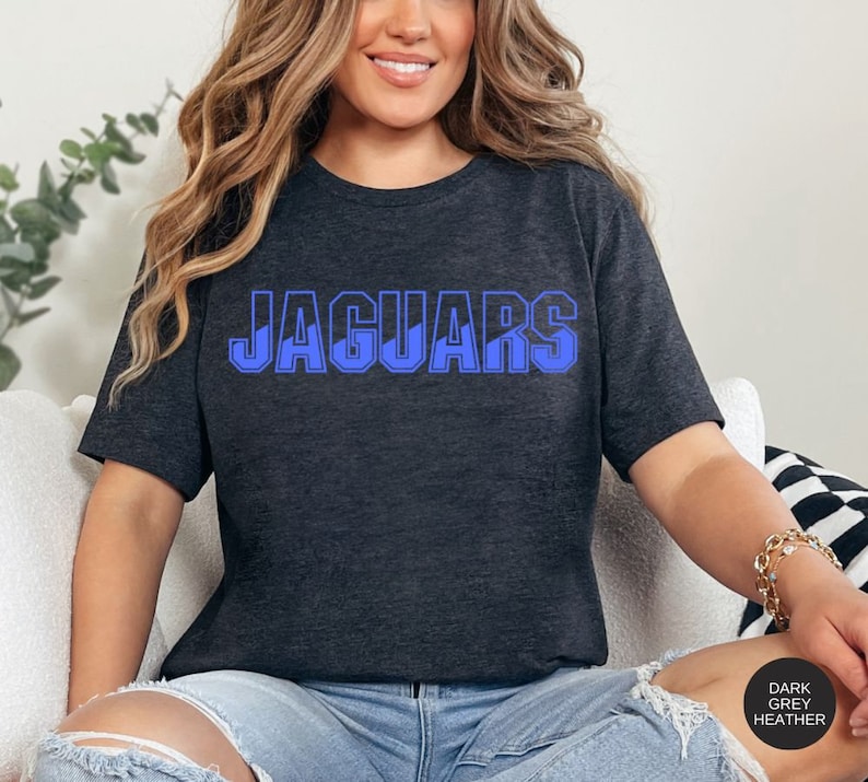 May include: A dark grey heather t-shirt with the word "JAGUARS" printed in blue on the front.