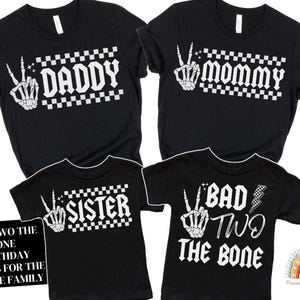 May include: Black t-shirts with white text and graphics. The shirts say "Daddy", "Mommy", "Sister", and "Bad Two The Bone".