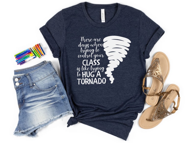 May include: A navy blue t-shirt with a white graphic of a tornado and the text "There are days when trying to control your CLASS is like trying to HUG A TORNADO".