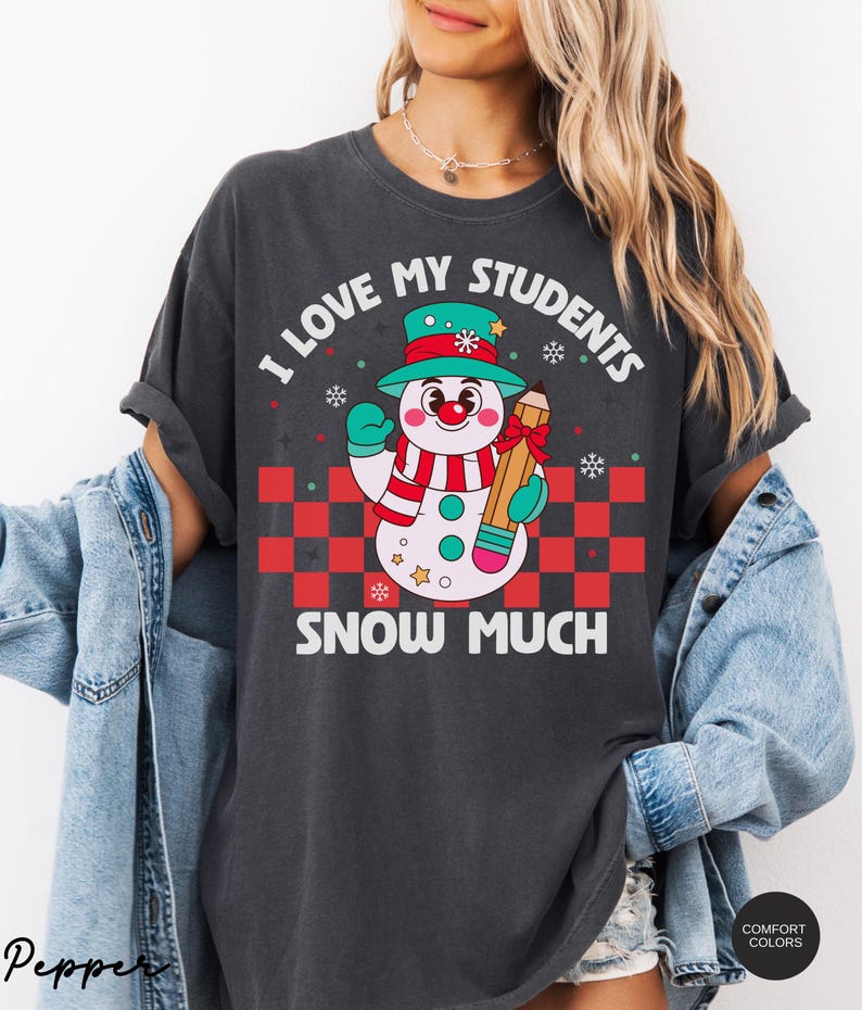 May include: A dark gray t-shirt with a snowman holding a pencil and the text "I love my students snow much".