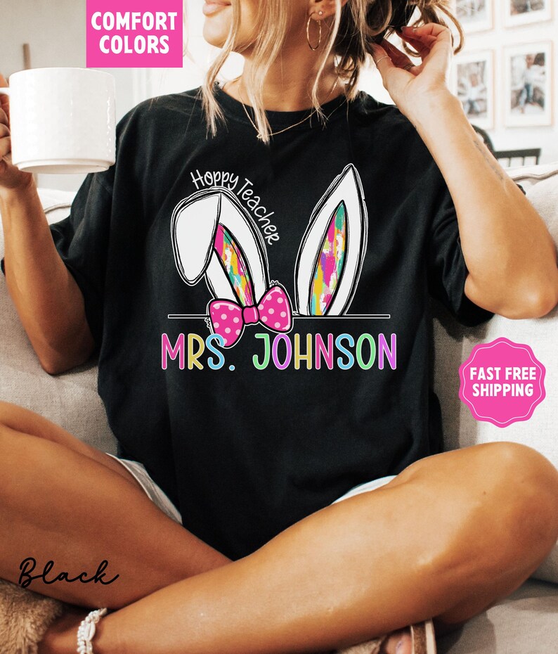 May include: Black t-shirt with a white bunny ear design and the text "Hoppy Teacher" above the text "MRS. JOHNSON".