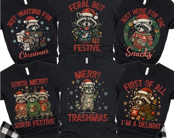 Könnte beinhalten: Schwarze Grafik-T-Shirts mit Weihnachts-Waschbär-Designs. Die Shirts zeigen Texte wie "Just Waiting For Christmas", "Feral But Festive" und "Merry Trashmas". Die Shirts werden auf einer schwarz-weiß karierten Oberfläche präsentiert.