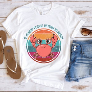 May include: White t-shirt with a retro-style graphic of a crab with the text "If Crabby Please Return To Beach".