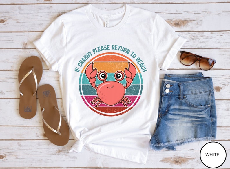 May include: White t-shirt with a retro-style graphic of a crab with the text "If Crabby Please Return To Beach".