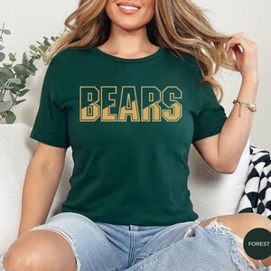 May include: A forest green t-shirt with the word "BEARS" printed in gold letters. The letters are outlined in black and have a mountain range design inside.