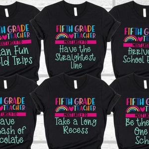 K&ouml;nnte beinhalten: Sechs schwarze T-Shirts mit einem Regenbogen-Design und dem Text "Fifth Grade Teacher" und einem anderen humorvollen Spruch auf jedem Shirt. Die Spr&uuml;che sind "Most Likely To Plan Fun Field Trips", "Most Likely To Have the Straightest Line", "Most Likely To Arrive to School Early", "Most Likely To Have a Stash of Chocolate", "Most Likely To Take a Long Recess", und "Most Likely To Be the Last One at School".