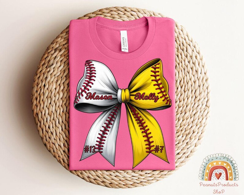 May include: Pink t-shirt with a white and yellow softball bow. The bow has the names "Mason" and "Molly" written on it. The shirt also has the numbers "#12" and "#7" on it.