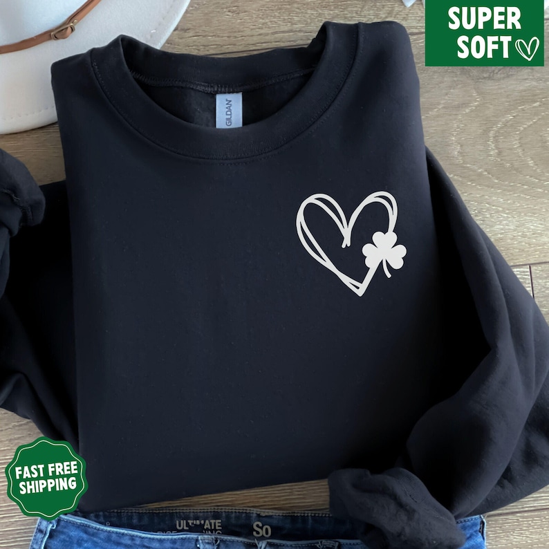May include: Black sweatshirt featuring a white heart and shamrock design. The heart is drawn in a simple, hand-drawn style.