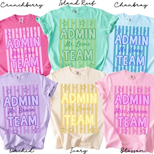 May include: Six short-sleeved t-shirts in various pastel colors including pink, mint green, light blue, lavender, ivory, and light pink. Each shirt features a vertical striped background, star accents, and the text ADMIN TEAM with a name.