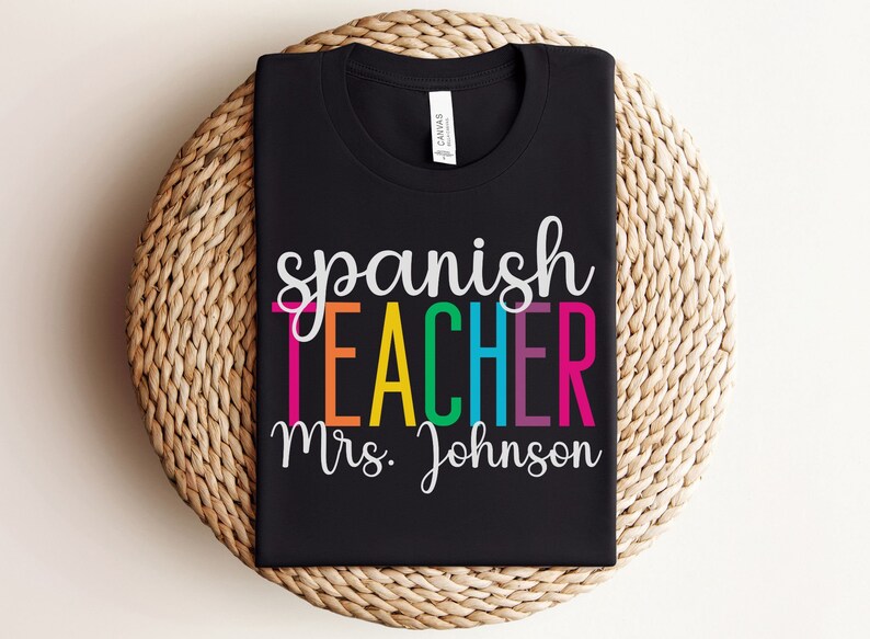 K&ouml;nnte beinhalten: Schwarzes T-Shirt mit dem Text "spanish teacher mrs. Johnson" in Regenbogenfarben.