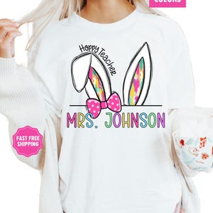 May include: White t-shirt with a colorful bunny ear design and the text "Hoppy Teacher" and "MRS. JOHNSON".