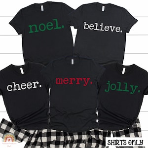 May include: Four black t-shirts with different Christmas-themed words printed on them in white, green, and red. The words are "cheer", "merry", "noel", and "jolly".