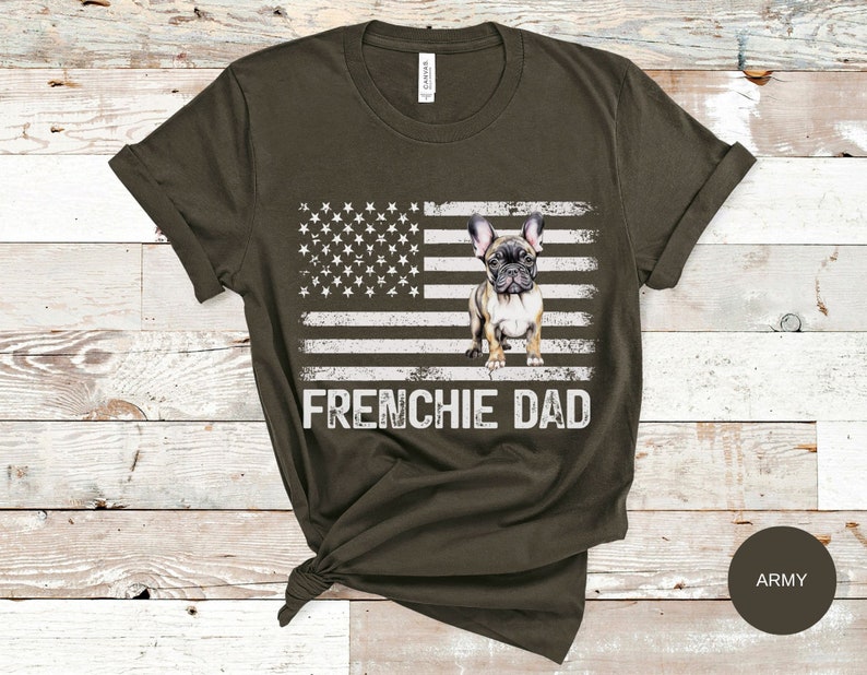 May include: A dark green t-shirt with a white American flag and a French bulldog standing in front of it. The text "FRENCHIE DAD" is printed below the flag.