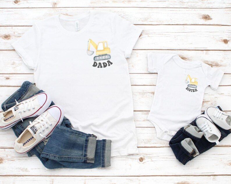 Peut inclure: T-shirts blancs et un body pour b&eacute;b&eacute; avec un dessin de pelle m&eacute;canique jaune et les mots "DADA" et "SISTER". Les chemises sont associ&eacute;es &agrave; des jeans bleus et des baskets blanches avec des d&eacute;tails rouges.