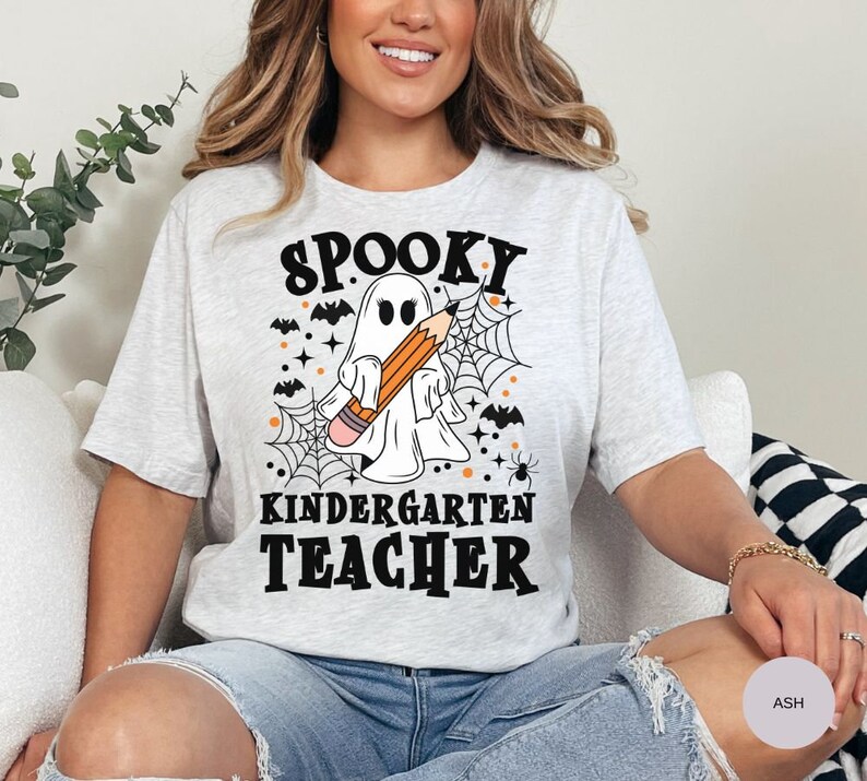 May include: A gray t-shirt with a spooky ghost holding a pencil and the text "Spooky Kindergarten Teacher".