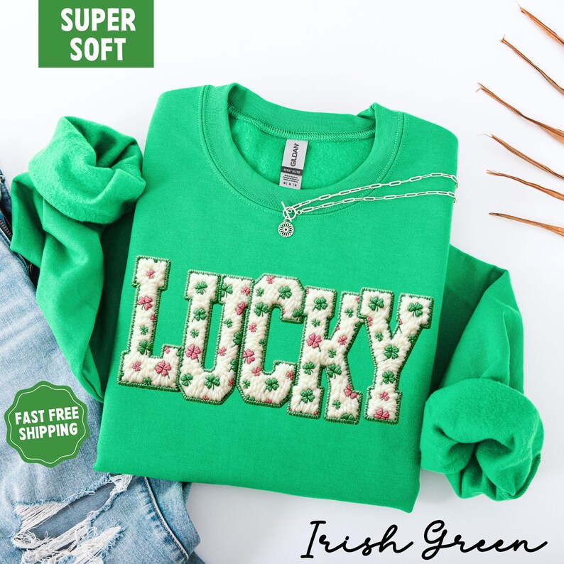 Pu&ograve; includere: Una felpa verde con la scritta "LUCKY" ricamata sul davanti con un motivo floreale. La felpa ha un girocollo e maniche lunghe. &Egrave; visibile una collana d'argento con un ciondolo. Le parole "Irish Green" sono scritte in corsivo.