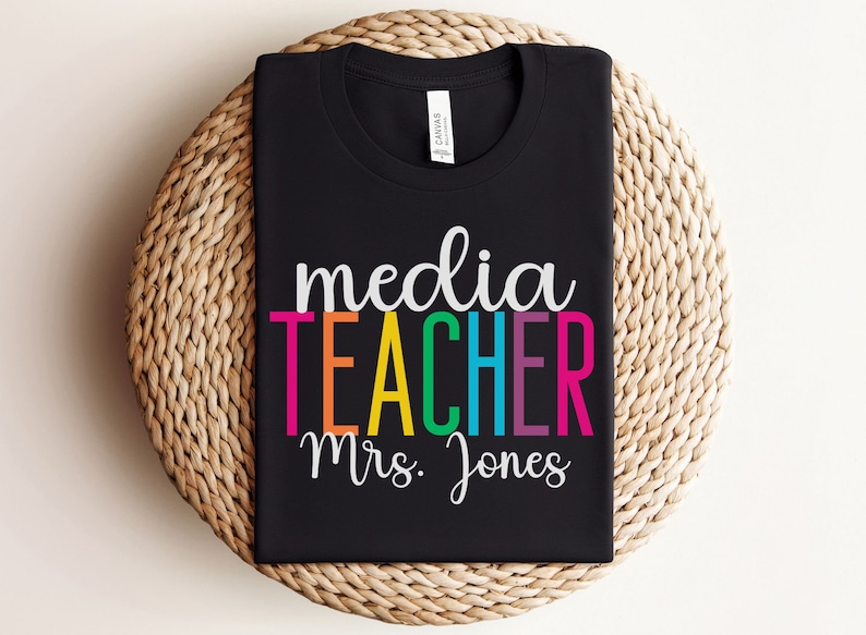 K&ouml;nnte beinhalten: Schwarzes T-Shirt mit dem Text "media teacher Mrs. Jones" in Regenbogenfarben.