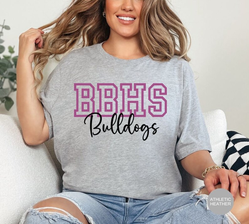 May include: A heather grey t-shirt with a purple outlined graphic that says "BBHS Bulldogs".