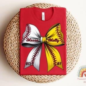 May include: Red t-shirt with a white and yellow softball bow. The bow has the names "Mason" and "Molly" on it, and the numbers "#13" and "#7" on the bottom.