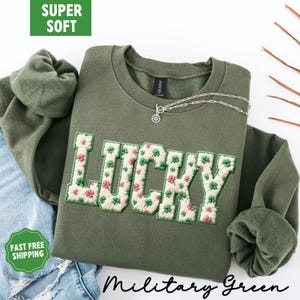 Pu&ograve; includere: Felpa verde militare con la scritta "LUCKY" ricamata con un motivo floreale a trifogli. La felpa ha un girocollo e maniche lunghe. Le parole "SUPER SOFT" e "FAST FREE SHIPPING" sono nell'immagine.