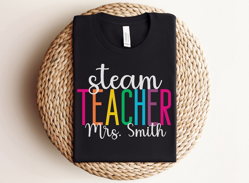 K&ouml;nnte beinhalten: Schwarzes T-Shirt mit dem Text "steam teacher" in Regenbogenfarben und "Mrs. Smith" in Wei&szlig; darunter.