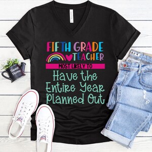 K&ouml;nnte beinhalten: Schwarzes V-Ausschnitt-T-Shirt mit dem Text "FIFTH GRADE TEACHER MOST LIKELY TO Have the Entire Year Planned Out" in bunten Farben mit einem Regenbogen- und Herz-Motiv.