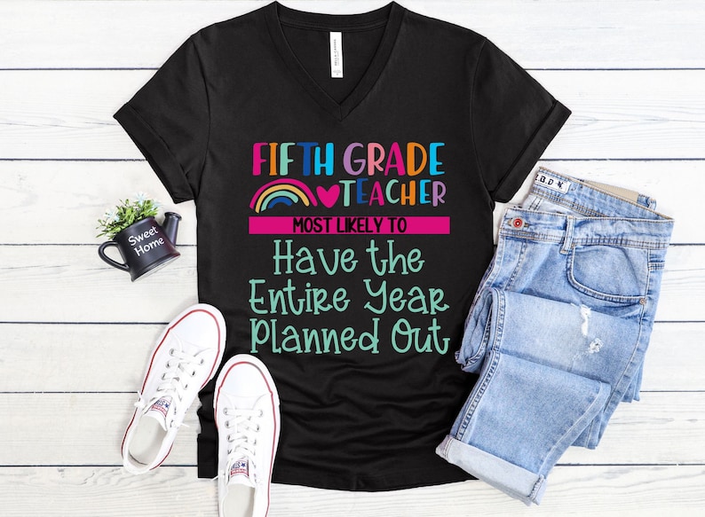 K&ouml;nnte beinhalten: Schwarzes V-Ausschnitt-T-Shirt mit dem Text "FIFTH GRADE TEACHER MOST LIKELY TO Have the Entire Year Planned Out" in bunten Farben mit einem Regenbogen- und Herz-Motiv.