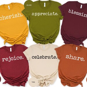 May include: Six different colored t-shirts with a white text design on each. The shirts are mustard yellow, olive green, maroon, heather cardinal, tan, and autumn. The text on the shirts reads "cherish", "appreciate", "blessing", "rejoice", "celebrate", and "share".