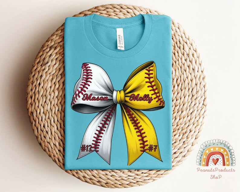 May include: A turquoise blue t-shirt with a white and yellow softball bow. The bow has red stitching and the names "Mason #13" and "Molly #7" are written on the bow.