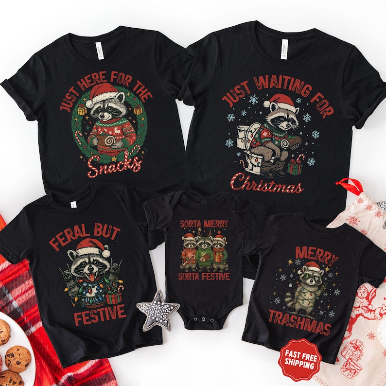May include: Black graphic t-shirts and a onesie featuring raccoons in Santa hats. The shirts have text that reads "Just Here For The Snacks", "Just Waiting For Christmas", "Feral But Festive", and "Merry Trashmas". The onesie says "Sorta Merry Sorta Festive".