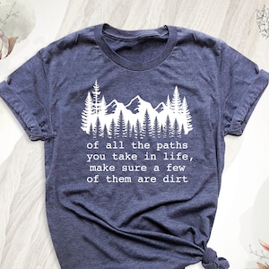 May include: A navy blue t-shirt with a white graphic of a mountain range and trees. The text "of all the paths you take in life, make sure a few of them are dirt" is printed below the graphic.