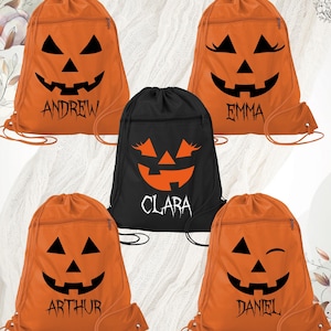 May include: Orange drawstring bags with black jack-o'-lantern faces and names: Andrew, Emma, Arthur, and Daniel. A black bag features a jack-o'-lantern face and the name Clara. The bags have a zipper pocket and drawstring closure, perfect for Halloween.