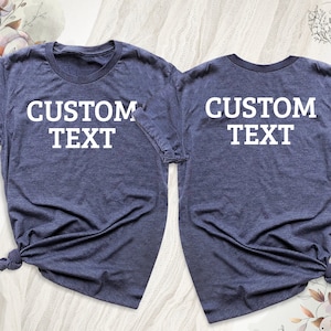 May include: Two navy blue t-shirts with white text that says "CUSTOM TEXT" on each shirt.