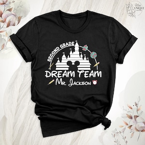 May include: Black t-shirt with a white graphic featuring a castle, Mickey Mouse ears, and the words "SECOND GRADE DREAM TEAM Mr. Jackson." Includes school-themed illustrations like pencils, a backpack, and a globe.