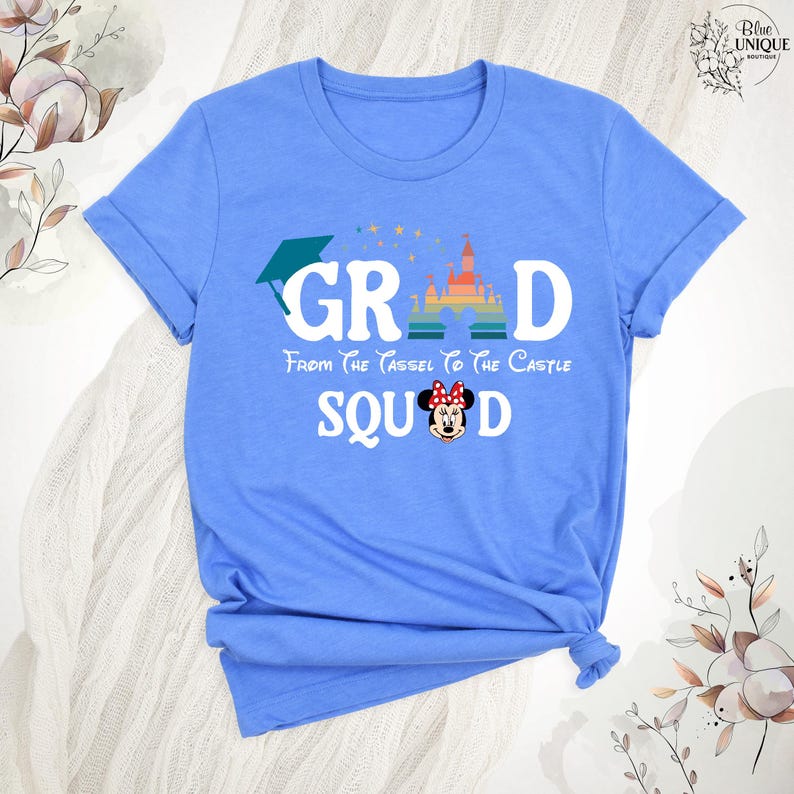 Puede incluir: Camiseta azul claro con un gr&aacute;fico de un gorro de graduaci&oacute;n, la palabra "GRAD", un castillo arco&iacute;ris y el texto "From the tassel to the castle SQUAD". Una imagen de dibujos animados de Minnie Mouse est&aacute; en el medio del texto "SQUAD".