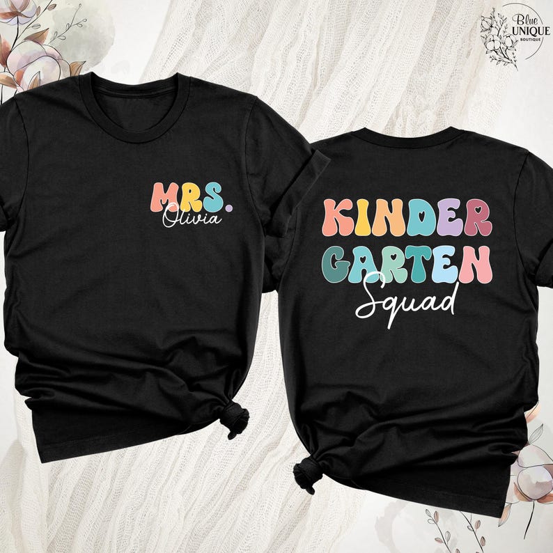 May include: Two black t-shirts with colorful text. One shirt says "MRS. Olivia" in pastel colors. The other says "KINDERGARTEN Squad" in a retro font. The shirts are knotted at the bottom.
