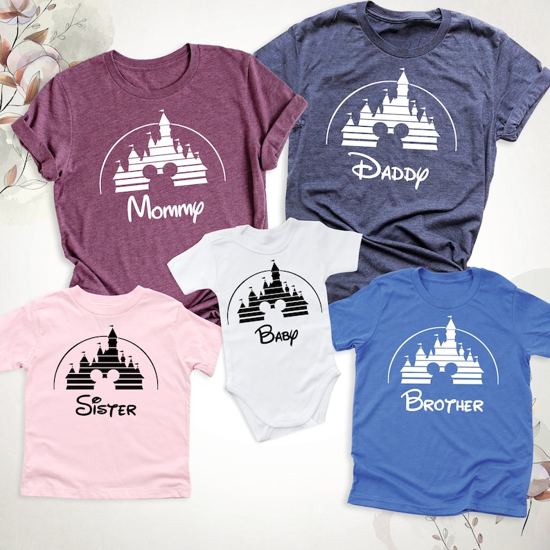 May include: A collection of family t-shirts and a baby bodysuit in shades like burgundy, navy, pink, white, and blue. Each garment displays a white castle graphic with Mickey Mouse ears and a family role: Mommy, Daddy, Baby, Sister, and Brother.